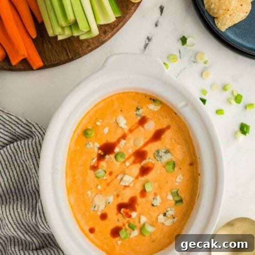 Slow Cooker Buffalo Chicken Dip: Creamy Cheesy Party Recipe 10 Cheesy Slow Cooker Buffalo Chicken Dip garnished and in bowl next to dish of celery, carrots, and tortilla chops