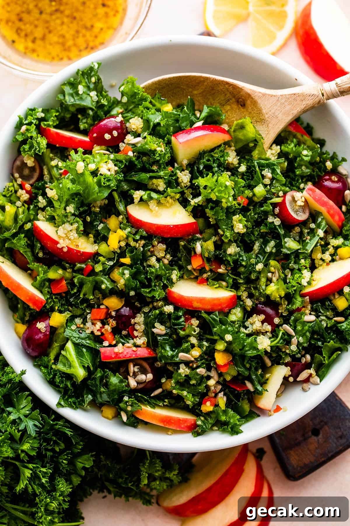 overhead shot of Crunchy Kale Quinoa Salad with slices of apples and lemons arranged around the salad.