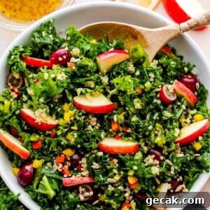 Crunchy Kale Quinoa Salad in a white bowl with a wooden spoon inside the bowl.