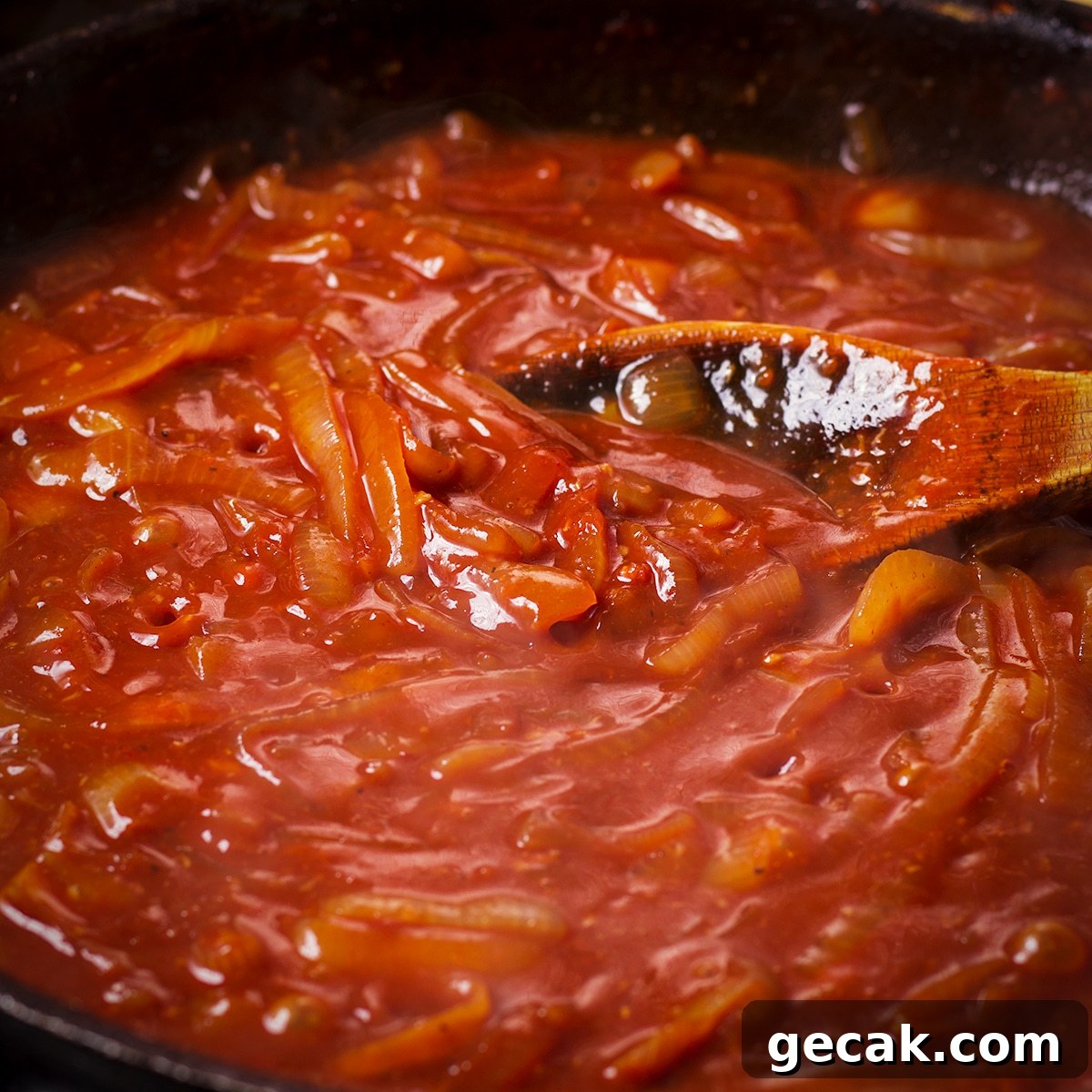 Using a wooden spoon to stir wine and broth into onions as the cook in a skillet.