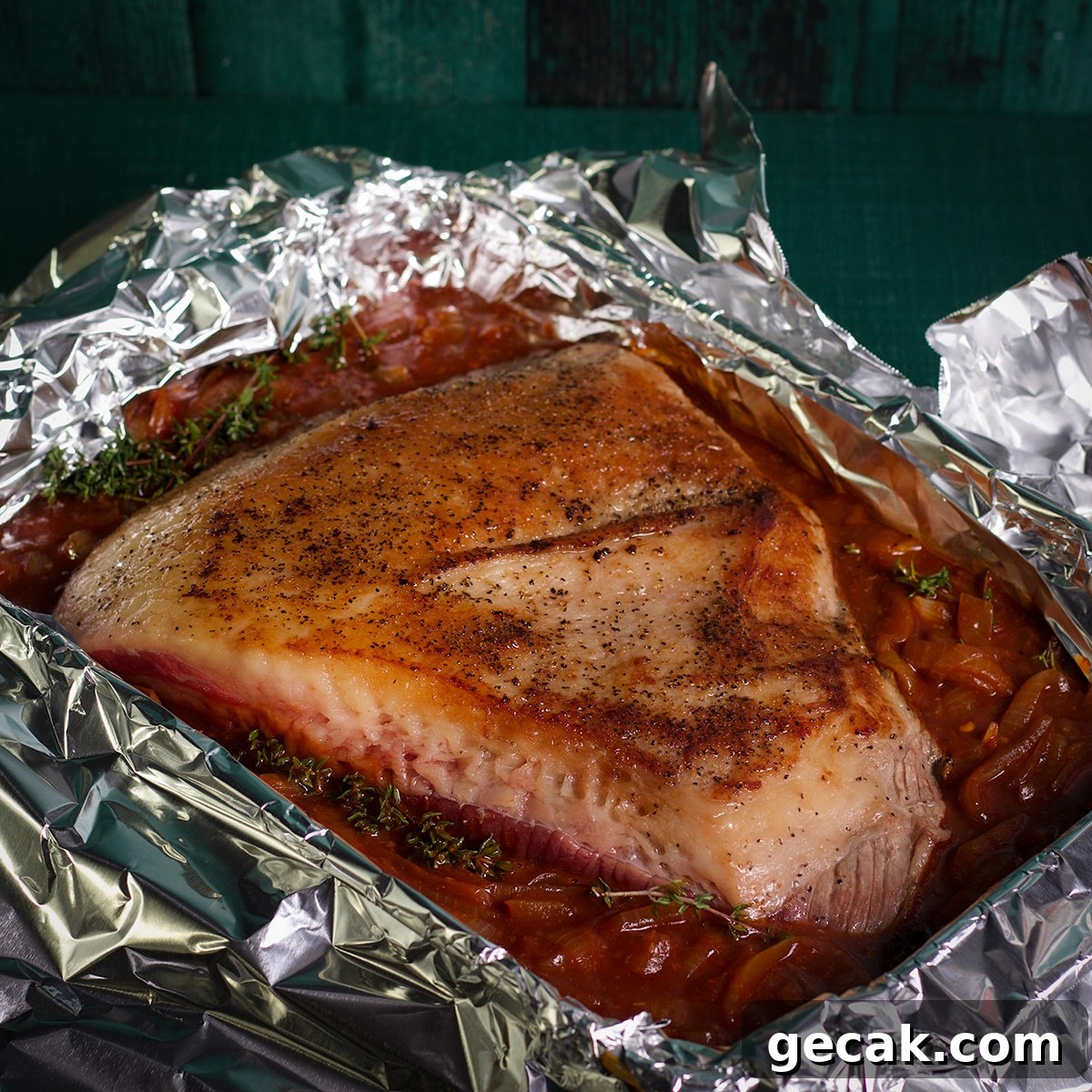 A beef brisket in a pan with sauce, ready to bake.