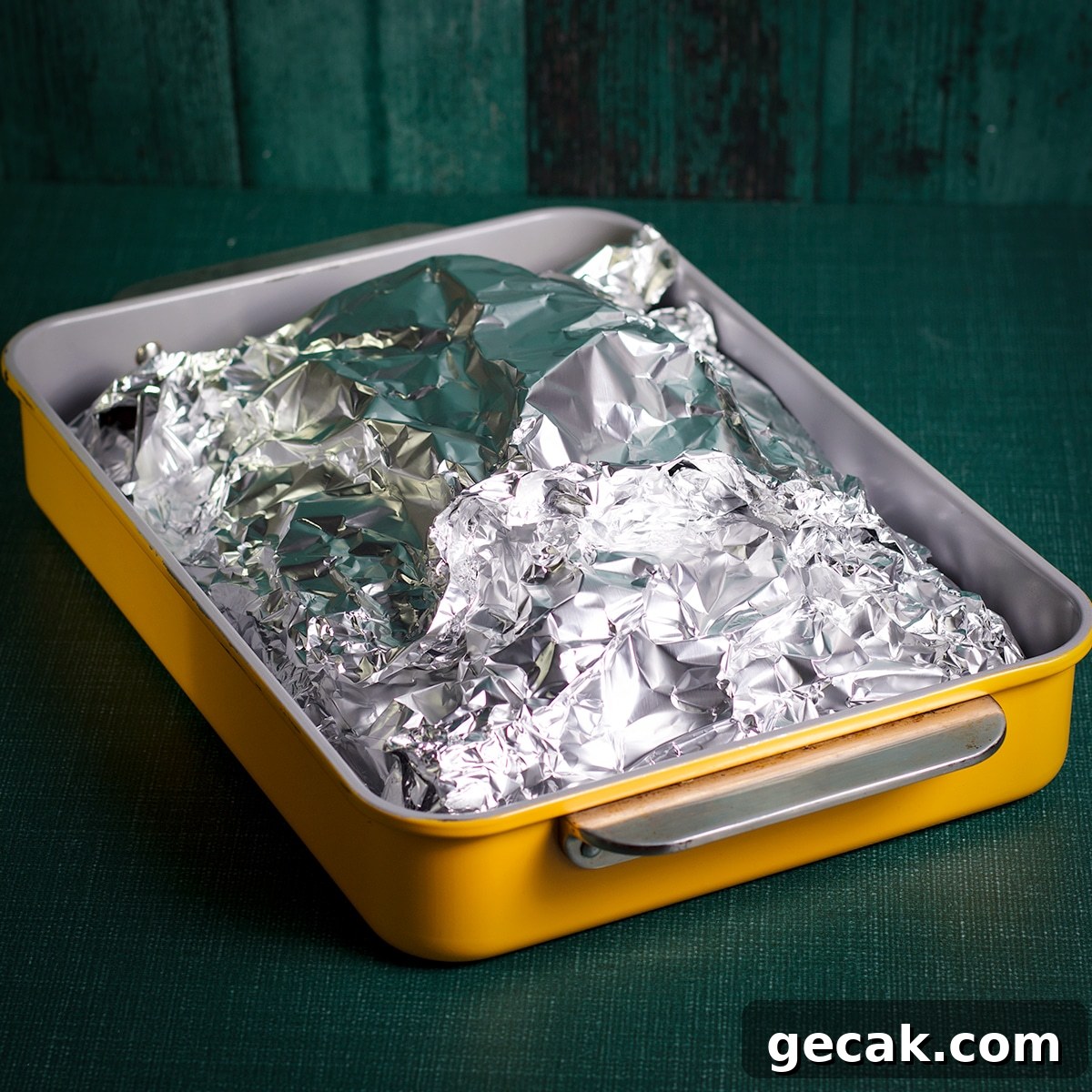 A brisket encased in foil in a baking dish.