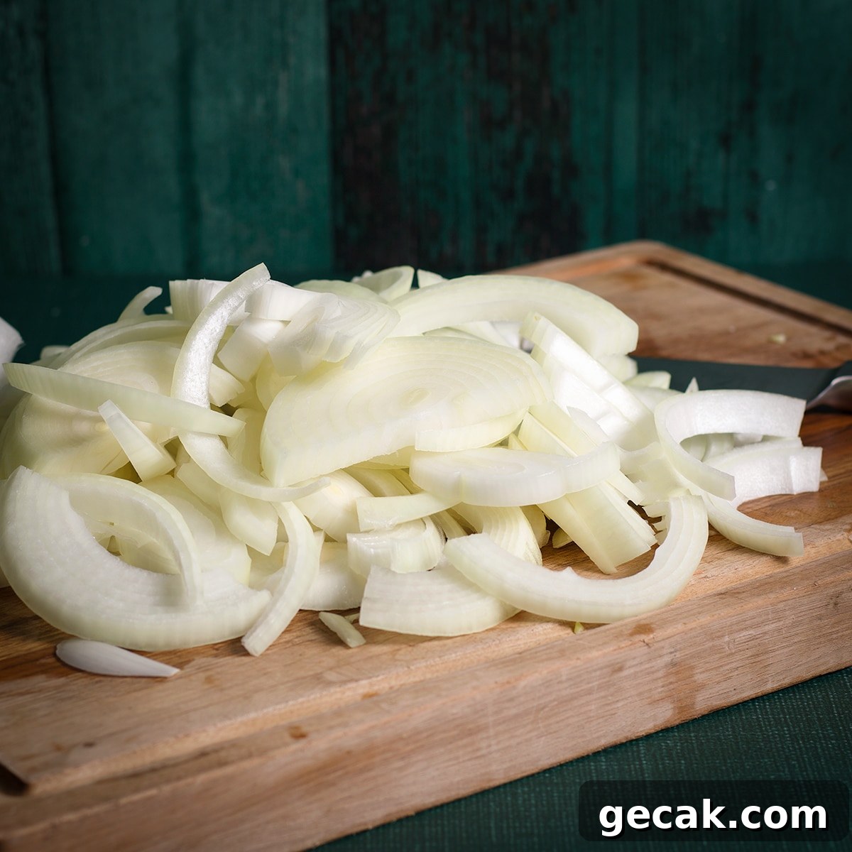 Sliced onions on a wooden cutting board.