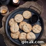 Vegan soul cakes on a metal tray on a dark surface with candles and cups of coffee.