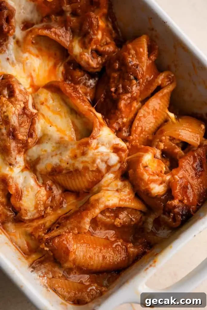 Vodka Ricotta Stuffed Pasta Bake with Creamy Tomato Sauce 13 Close-up of baked stuffed pasta shells coated in vodka sauce and melted cheese, showing the tender, cheesy filling inside.