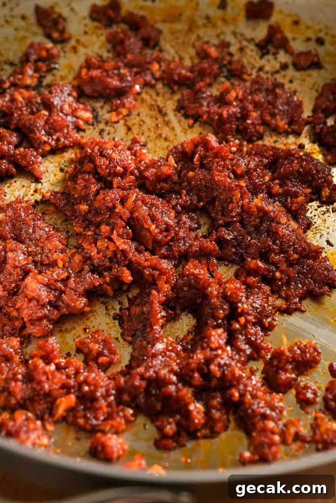 Vodka Ricotta Stuffed Pasta Bake with Creamy Tomato Sauce 5 Caramelized tomato paste mixture with garlic and spices in a pan, forming the base for a rich vodka sauce.