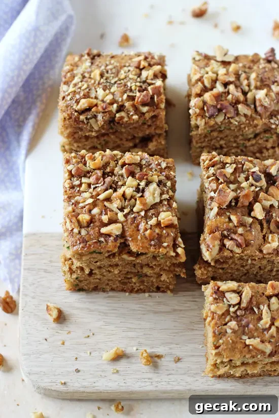 Several squares of Cinnamon Zucchini Bread on a cutting board with a blue napkin to the side.