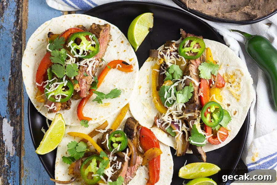 Steak fajitas with flour tortillas on a black plate on a blue distressed wood background