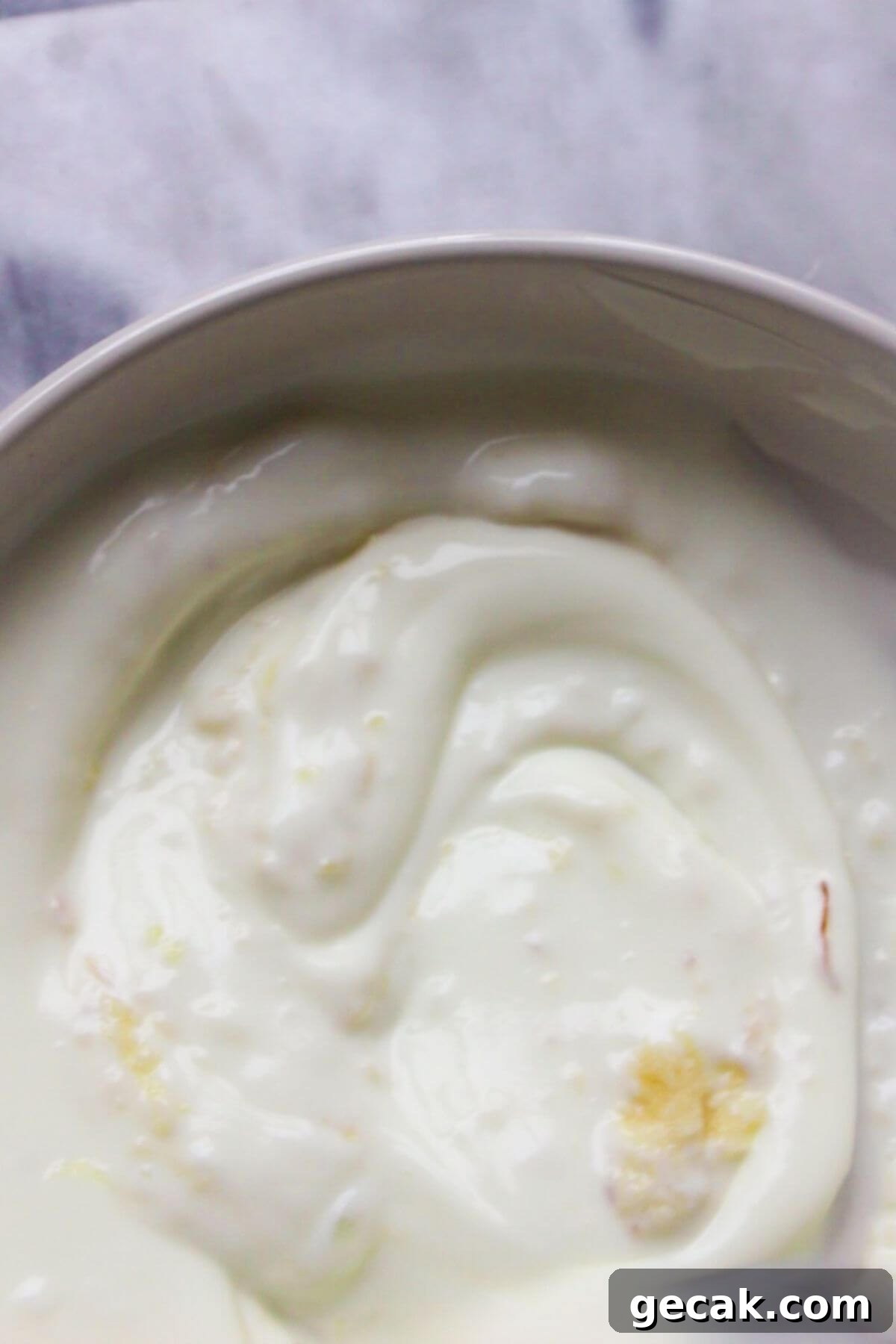 Turkish-Style Poached Eggs with Tomato and Yogurt Sauce 4 Yogurt and crushed garlic in a small white bowl on a grey marble background.
