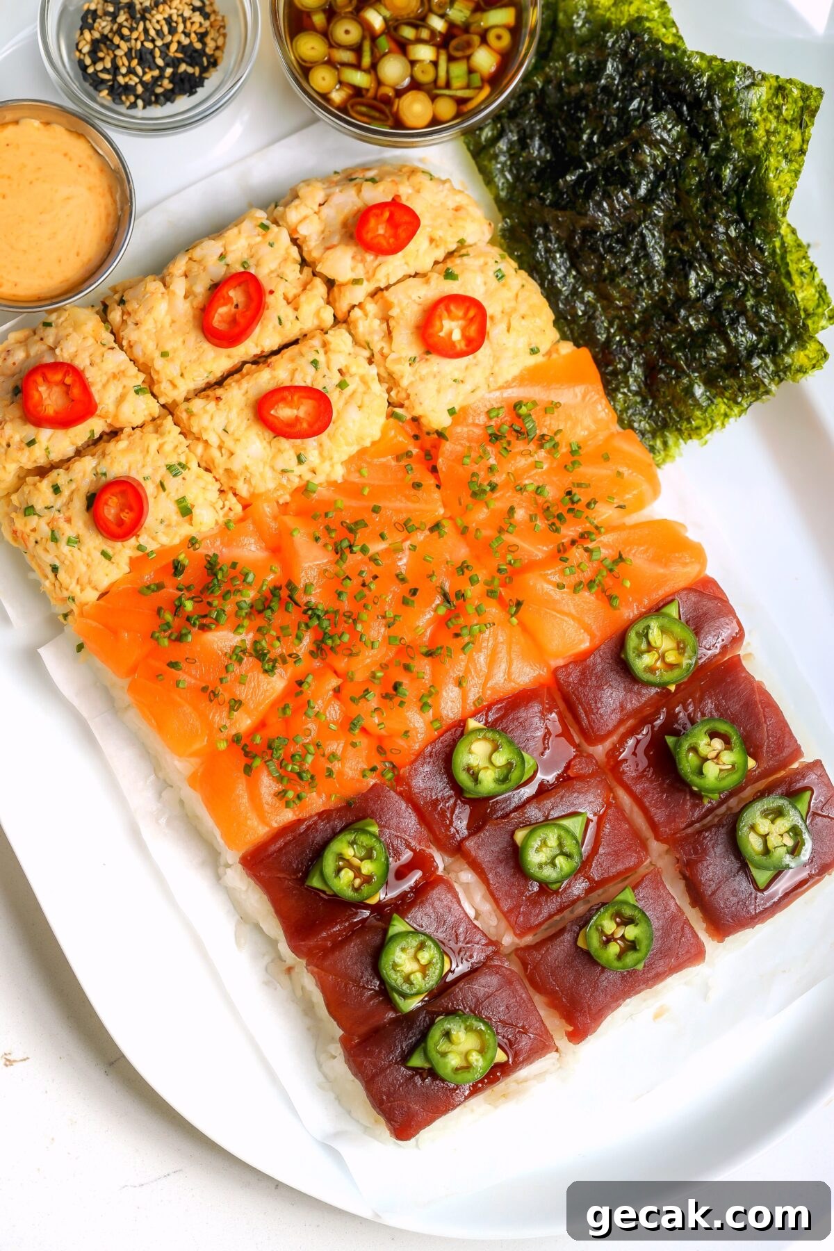 Nigiri-style sushi board with rice on the bottom and three different toppings, spicy crab, salmon and bluefin tuna. On a platter with different sauces on the side.