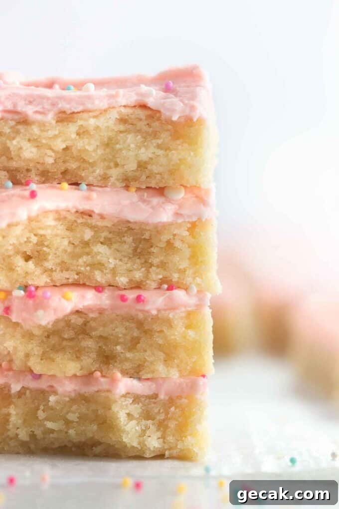 Stack of soft frosted sugar cookie bars with pink frosting and sprinkles