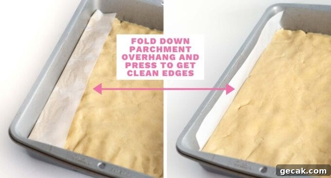 9x13 of sugar cookie dough with parchment overhang pressing down dough to get clean edges