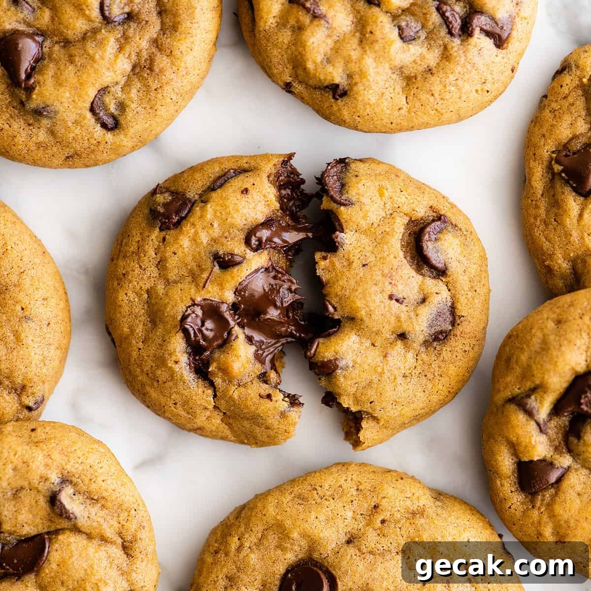 overhead view of a Pumpkin Chocolate Chip Cookie cut in half surrounded by 7 other pumpkin chocolate chip cookies