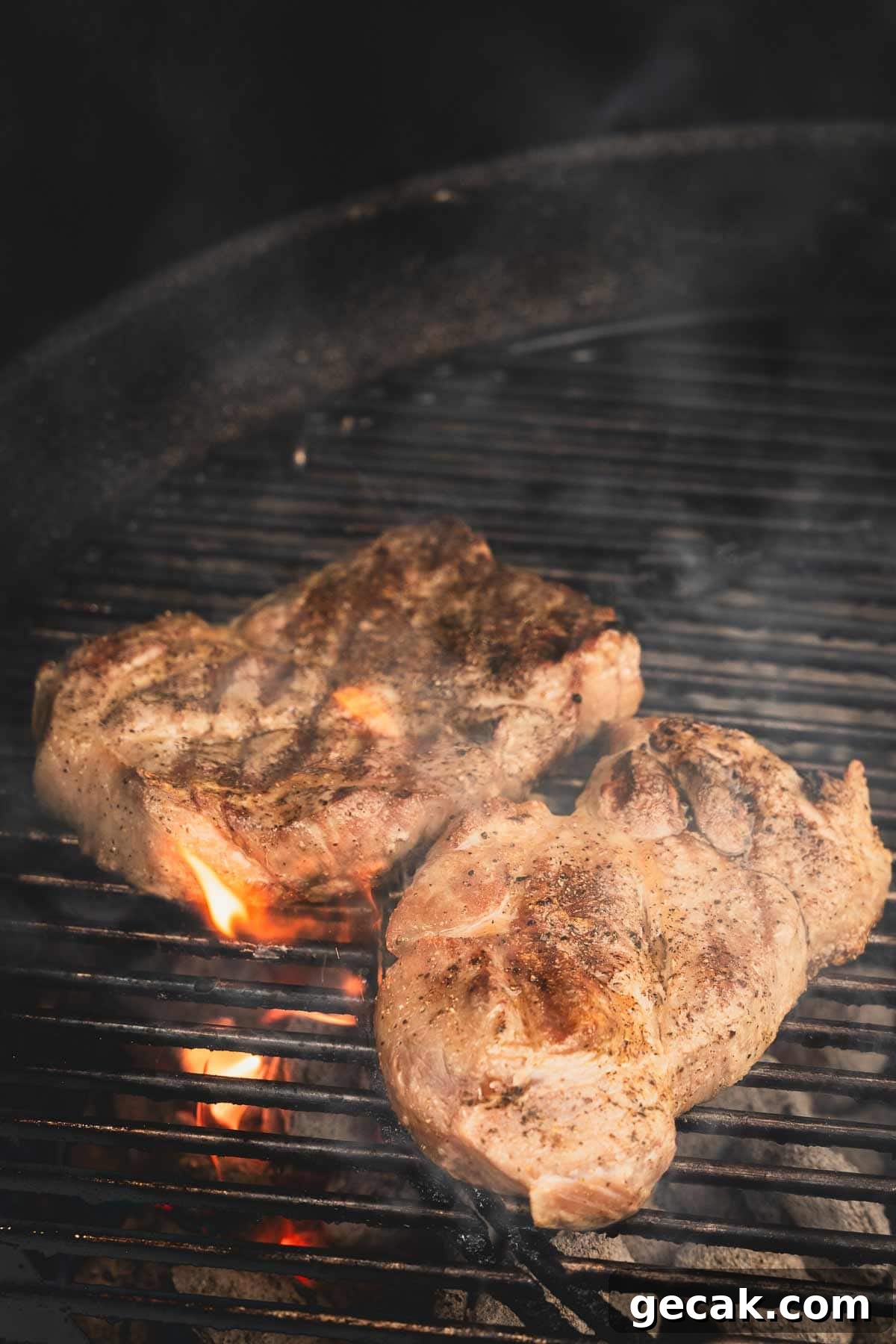 Juicy Grilled Pork Steaks with Garlic Herb Marinade 2 pork shoulder steaks on a charcoal grill