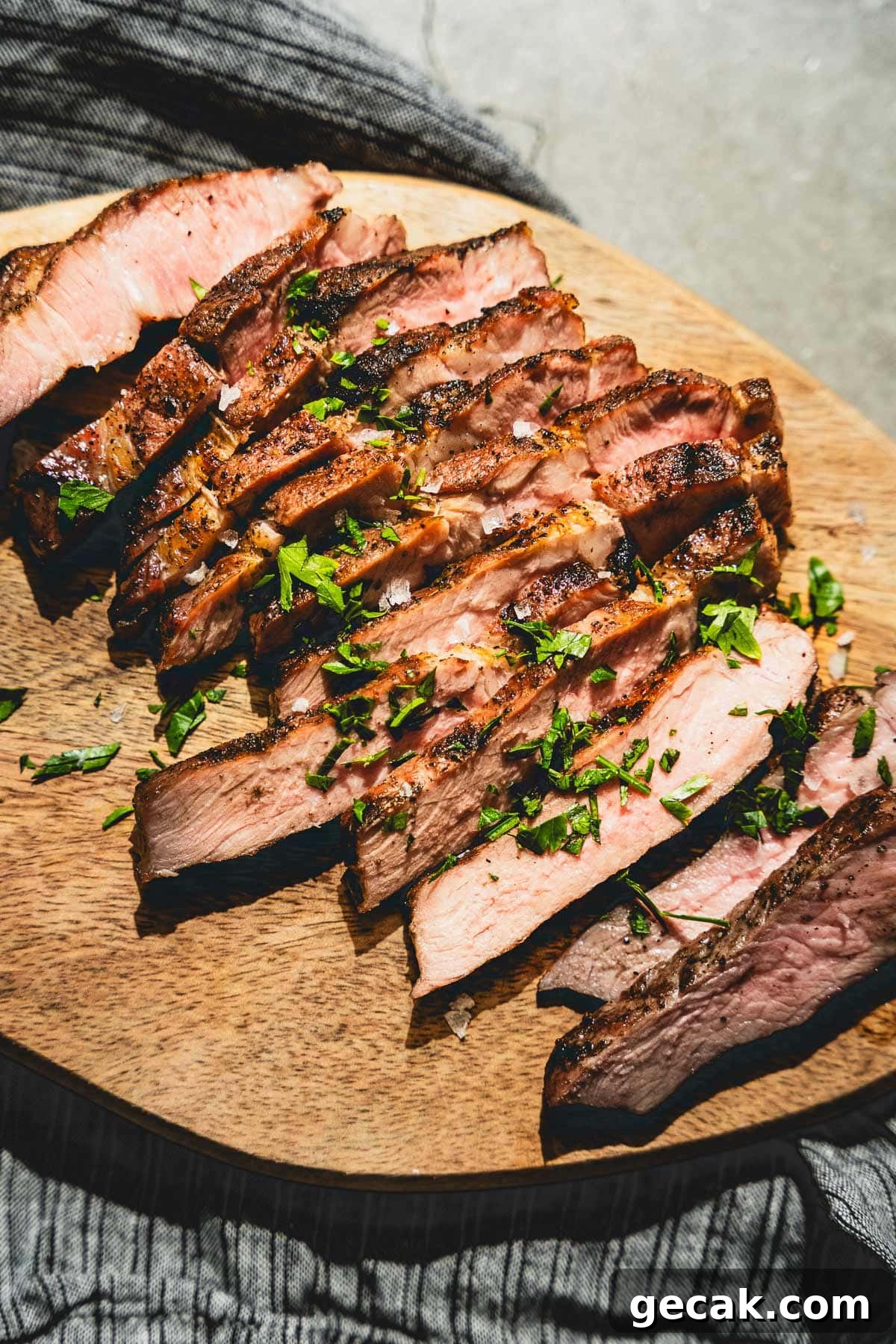 Juicy Grilled Pork Steaks with Garlic Herb Marinade 4 grilled pork steaks sliced on a cutting board vertical