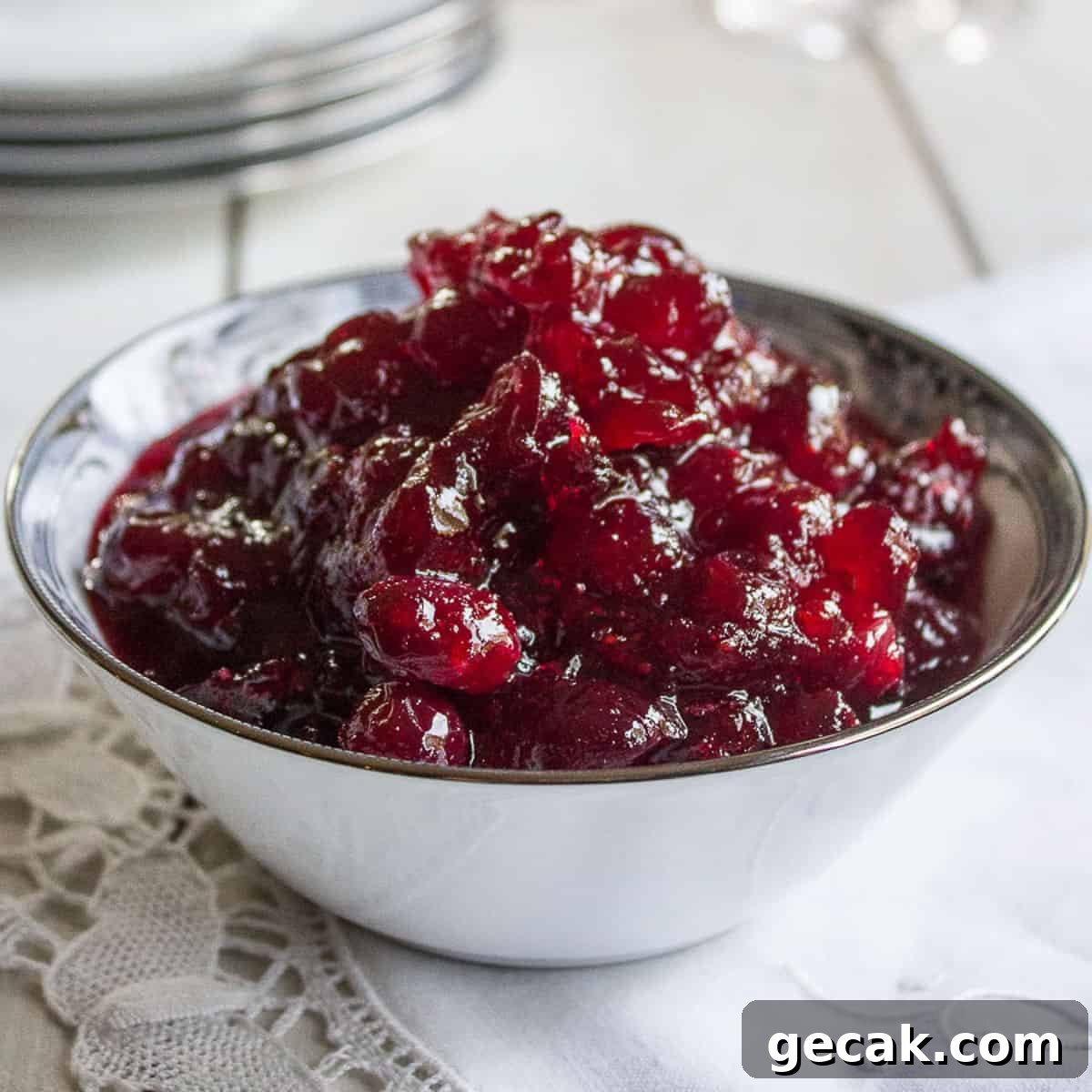 Cranberry sauce in a white china dish on top of a white napkin.