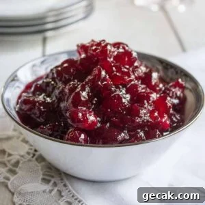 Cranberry sauce in a white china dish on top of a white napkin.