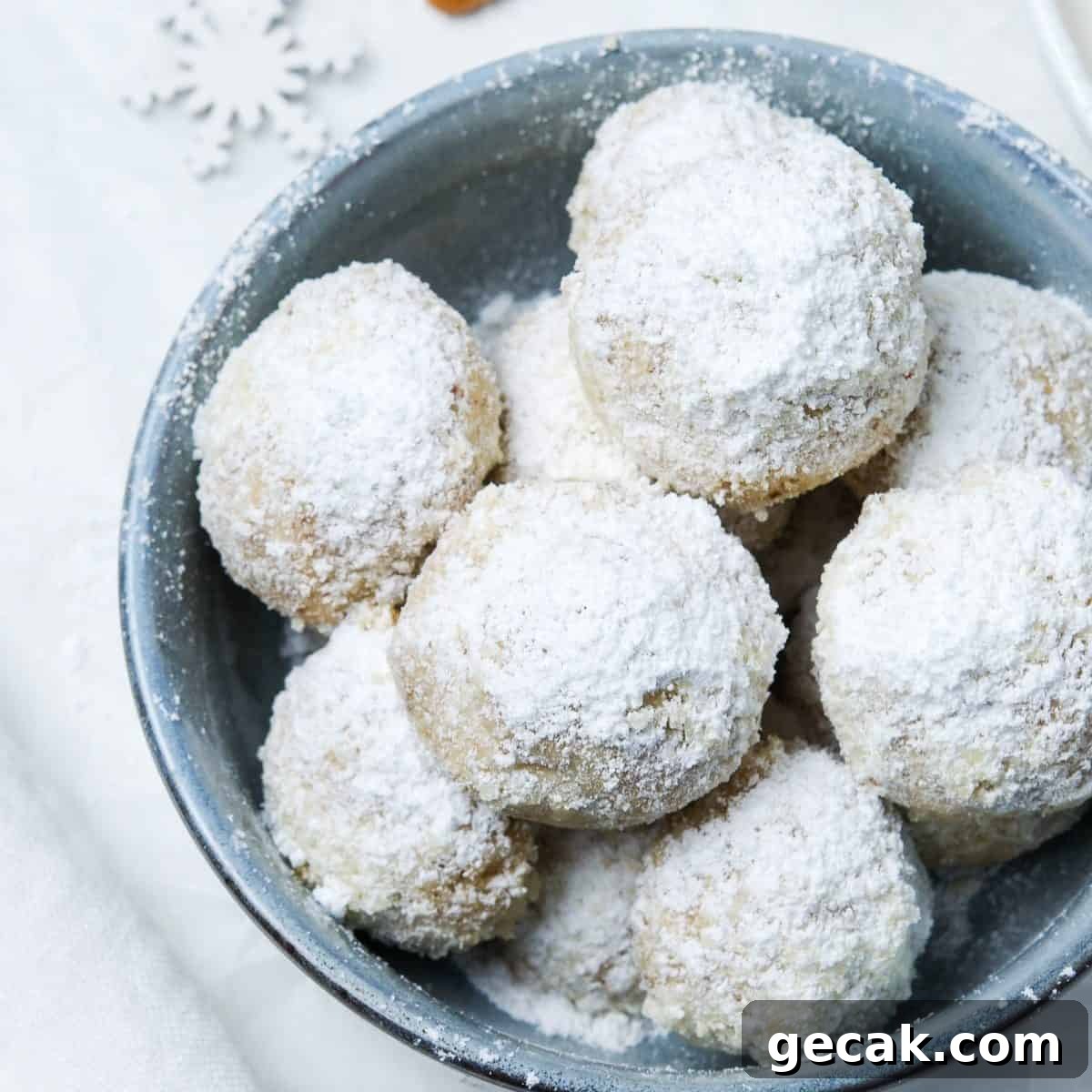 Round blue dish of cookies dusted with icing sugar.