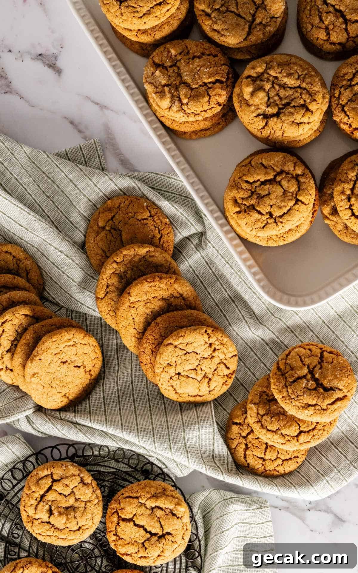 Molasses cookies spread out on a linen napkin with a platter of cookies.