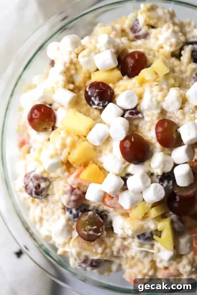 Classic Frog Eye Salad Recipe — Creamy Ambrosia-Style Dessert 2 frog eye salad recipe in a glass bowl topped with marshmallows and grapes.