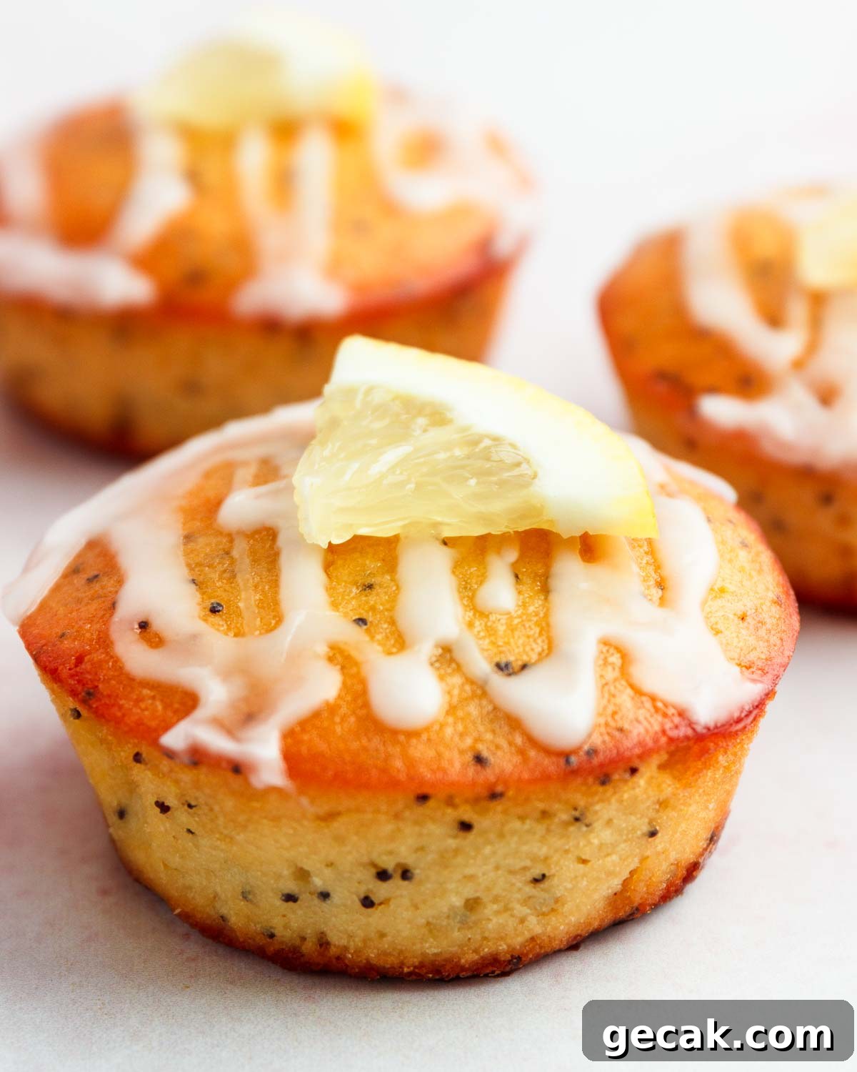 Three lemon iced lemon poppy seed muffins.