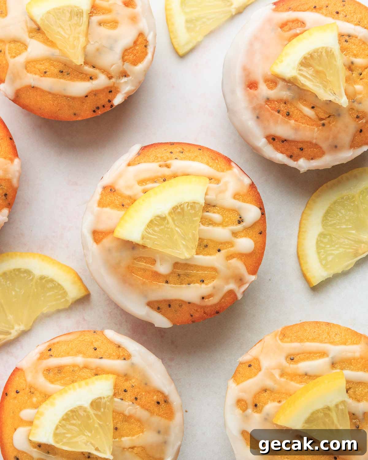 Six keto lemon poppy seed muffins with lemon icing and lemon wedges.