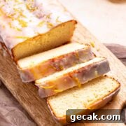 A keto iced lemon loaf that is sliced on a cutting board.