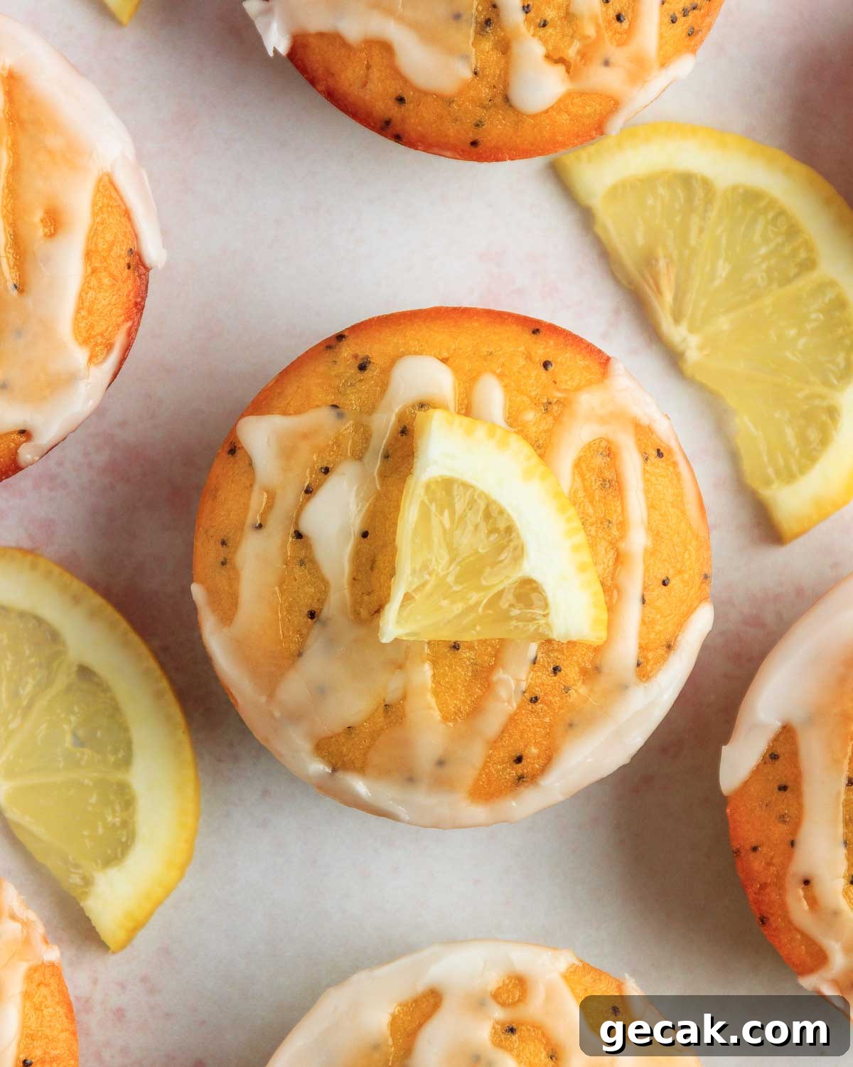 Six keto lemon poppy seed muffins with lemon icing and lemon wedges.
