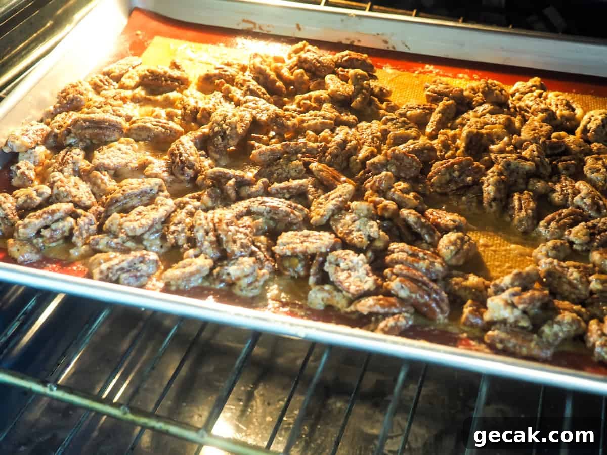 Bourbon Candied Pecans with Sweet & Spicy Glaze 9 a tray of candied pecans baking in the oven.