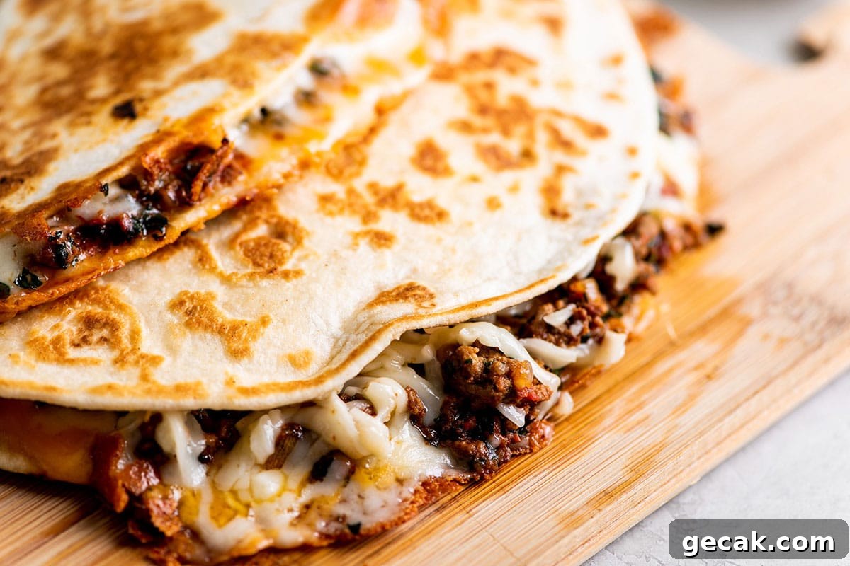 Cheesy Beef Comfort Recipes for Cozy Weeknight Meals 2 Cheesy Ground Beef Quesadillas stacked on wood cutting board.
