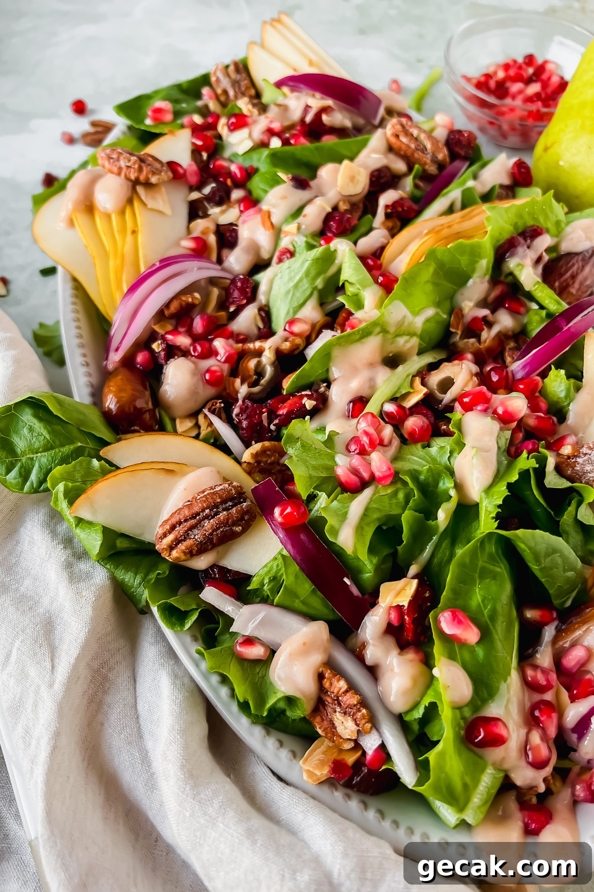 pear and pecan salad on white serving plate with homemade pear vinaigrette drizzled on top.