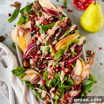 pear and pecan salad on white serving plate with homemade pear vinaigrette drizzled on top.