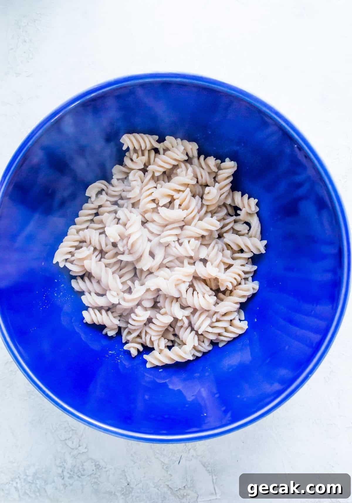 A large bowl filled with cooked spiral noodles.