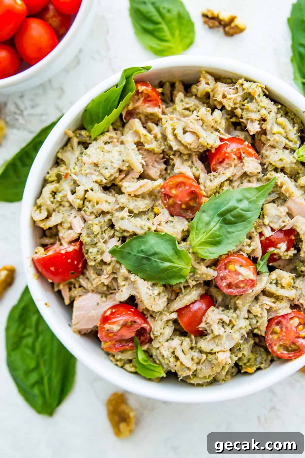 A bowl of tuna pasta salad topped with fresh basil leaves.