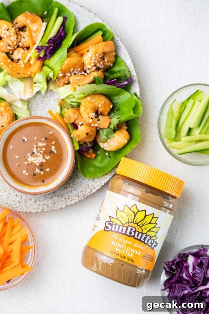 Spicy Thai Shrimp Lettuce Wraps — Low-Carb Dinner Idea 3 A jar of SunButter next to a plate of shrimp lettuce wraps.