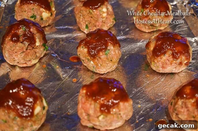 BBQ glazed meatballs on a foil-lined baking sheet.