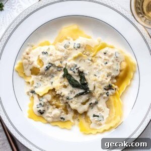 A plate of lobster ravioli topped with a creamy sauce, herbs, and grated cheese, served on a white dish with a silver rim.