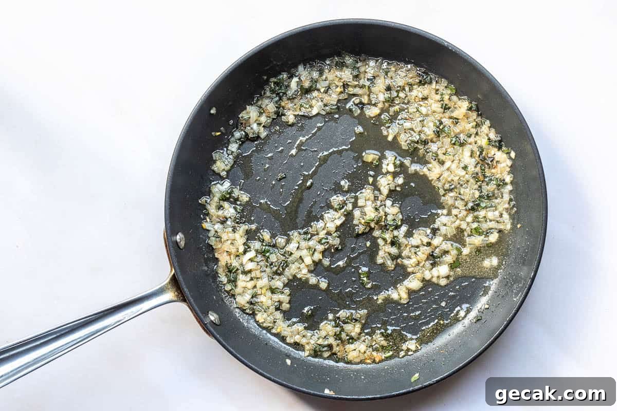 A frying pan containing chopped shallots and sage being sautéed in oil.