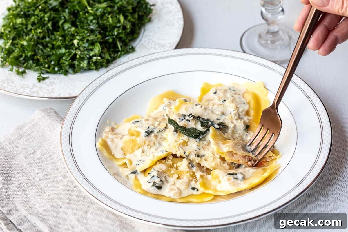 A plate of lobster ravioli with sauce and sage, with a fork taking a bite; a side of chopped greens is visible in the background.