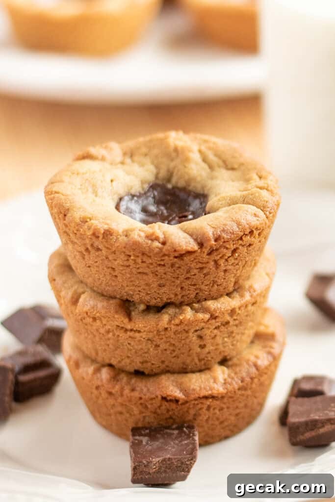 stack of peanut butter cookie cups with pieces of chocolate around it on a white plate