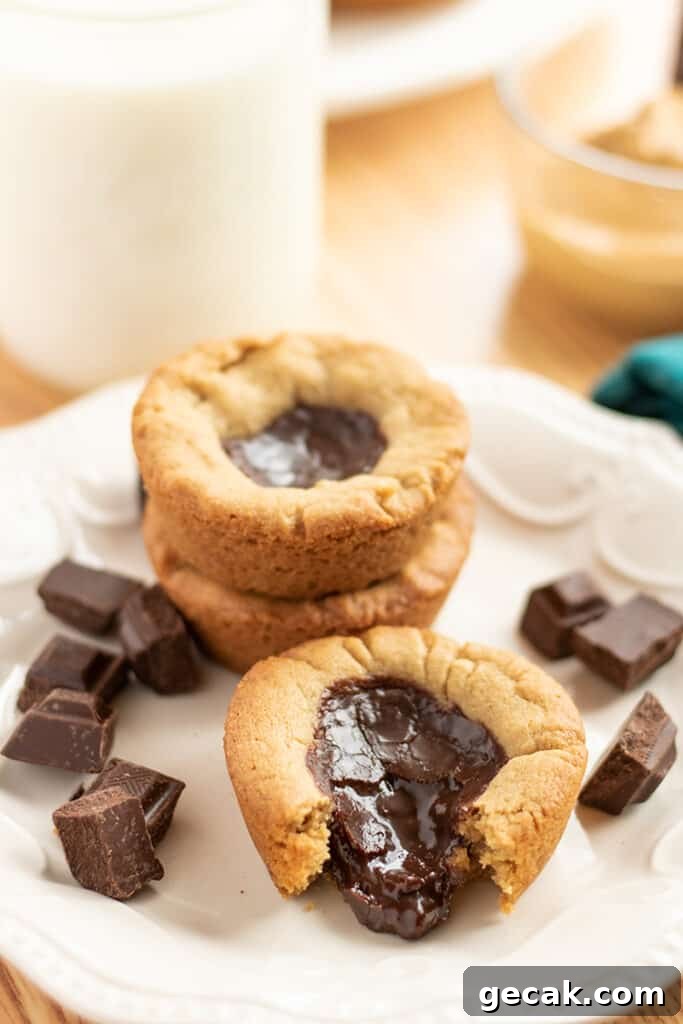 plate with a cookie cup on it with chocolate coming out of it and chocolate bites around it
