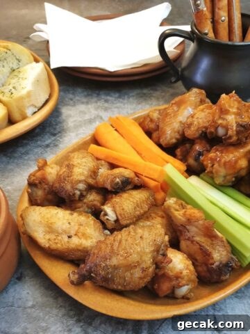 A piate of crispy air-frier crispy chicken wings on a table with carrot and celery sticks.