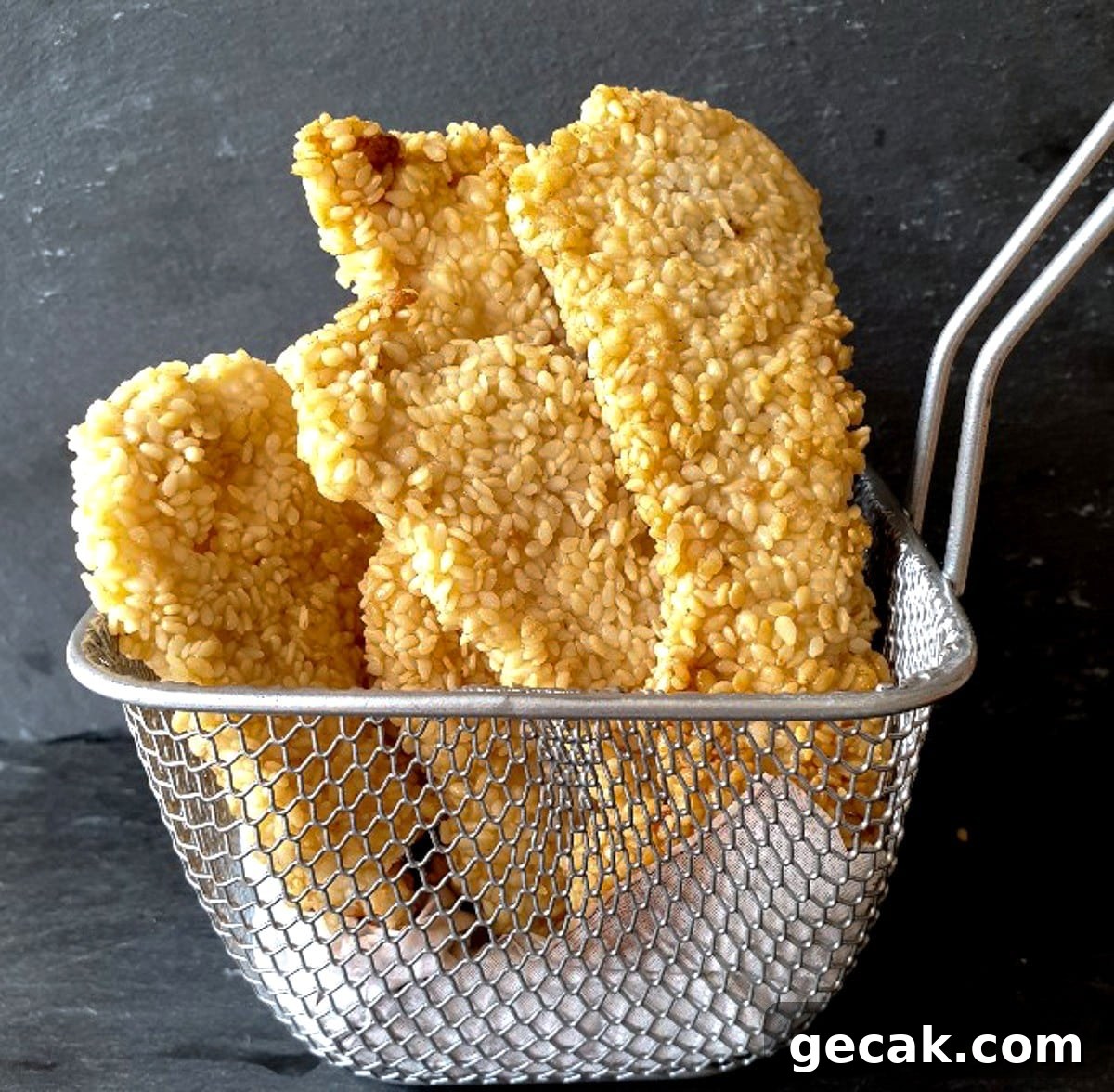 Crispy Sesame Chicken Strips Without Breadcrumbs — Low-Carb Crunch 3 Sesame chicken strips in a wire small basket.