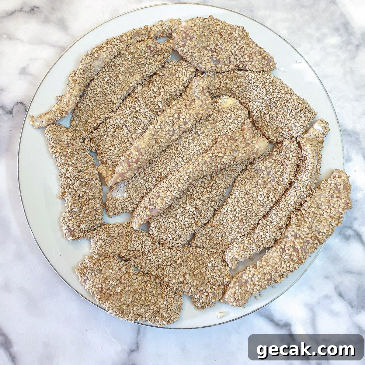 Crispy Sesame Chicken Strips Without Breadcrumbs — Low-Carb Crunch 8 Chicken strips coated in sesame seeds on a white plate.