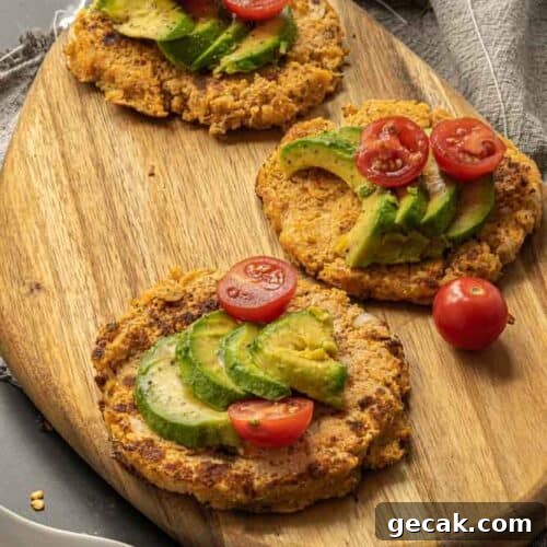 Savory Cauliflower Pancakes with Herbs and Parmesan 18 angled photo of cauliflower pancakes on a wood cutting board topped with avocado and tomatoes