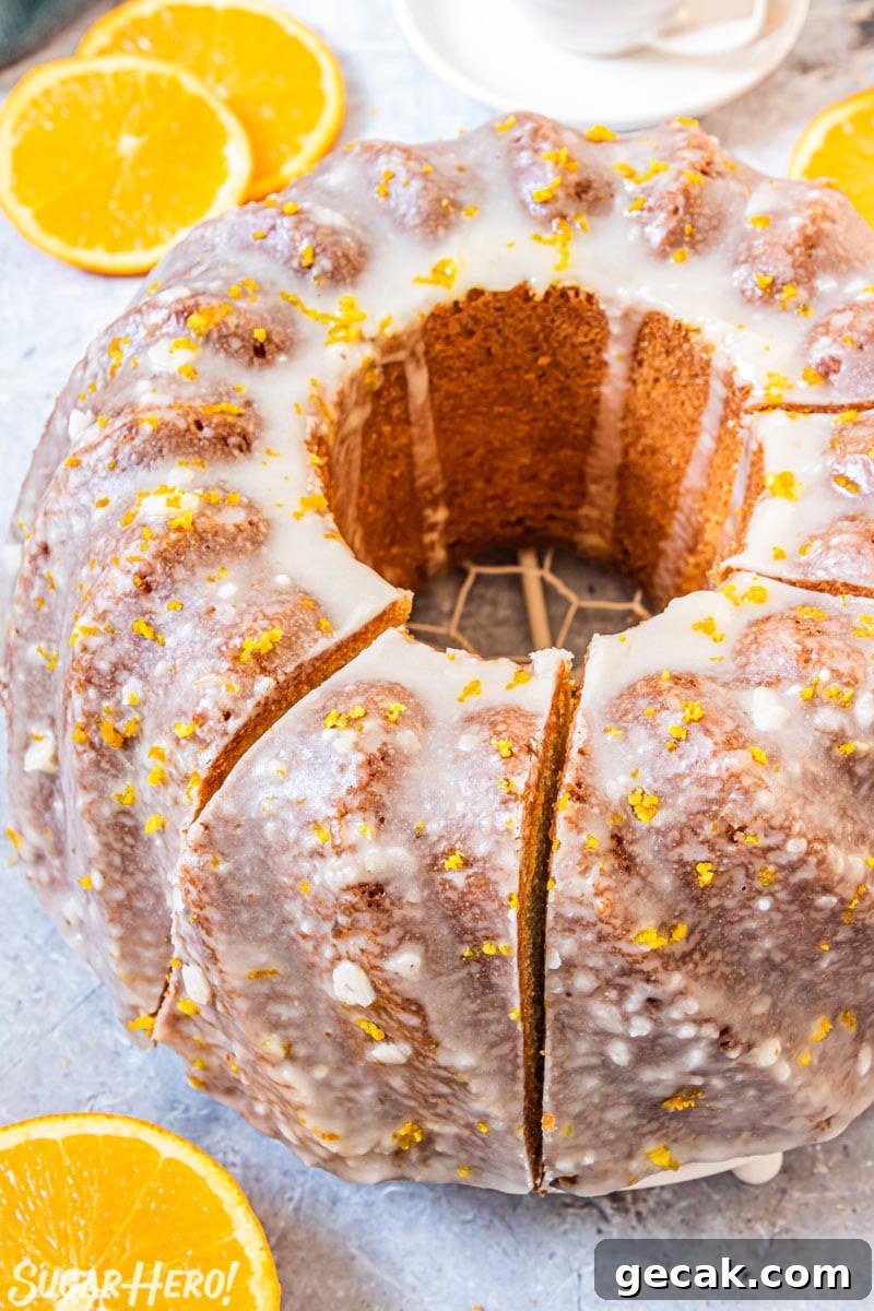 Orange bundt cake on a wire rack, sliced into pieces.