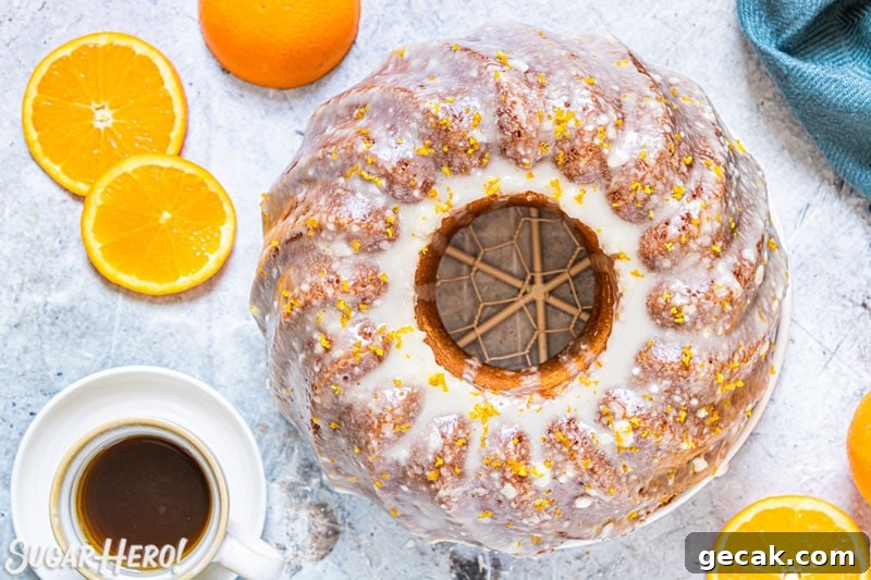 Overhead shot of orange bundt cake with orange glaze, with coffee cup at the side.