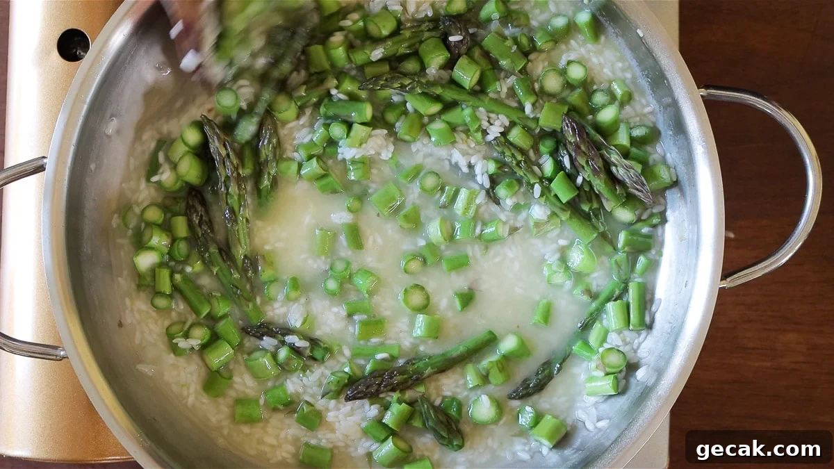 cooking the vegan risotto with vegetable broth and asparagus