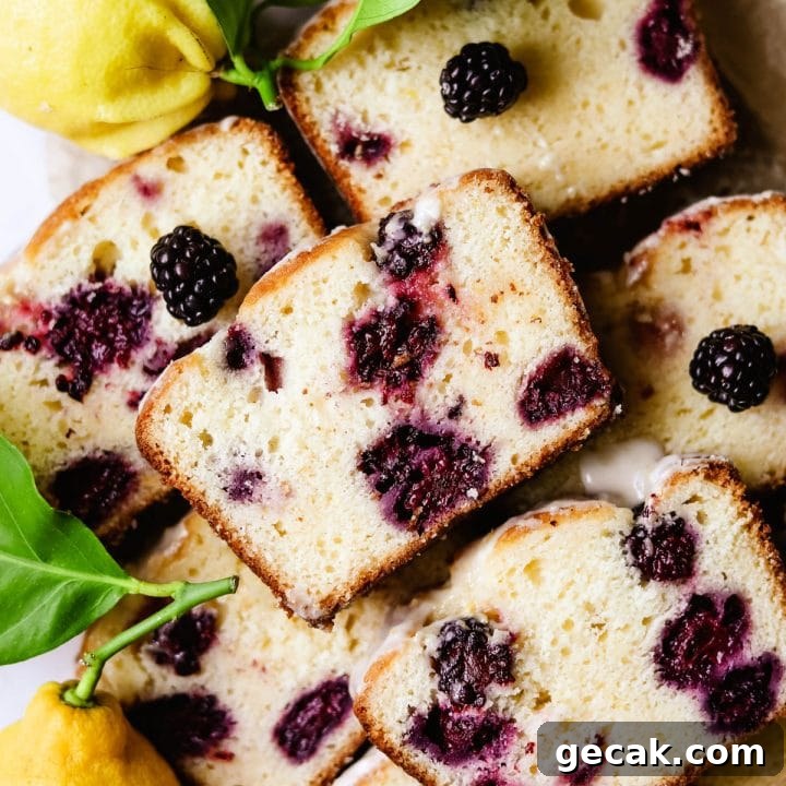 Blackberry lemon bread loaf cut into slices surrounded with real lemons and lemon zest icing.