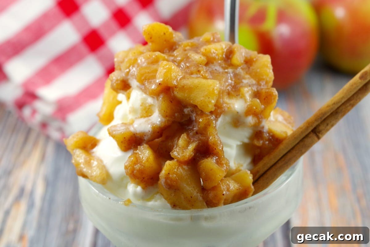 apple cinnamon topping on frozen yogurt in ice cream dish with spoon and cinnamon stick, apple and checked cloth in background
